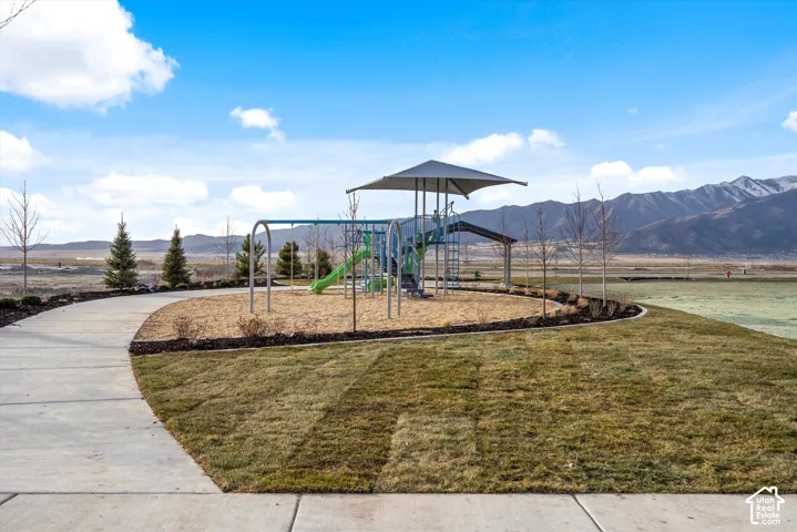 Community playground with a swing set and slide, featuring a covered play structure
