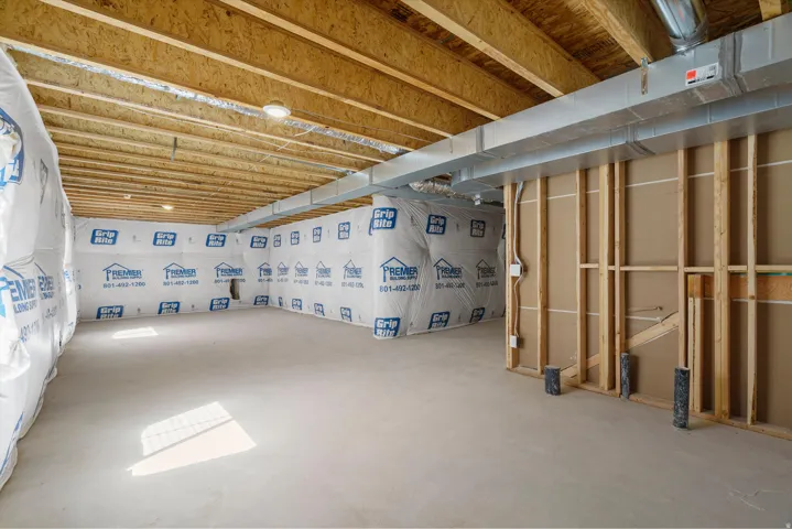 Unfinished basement with exposed ceiling joists, concrete flooring, and partial wall framing