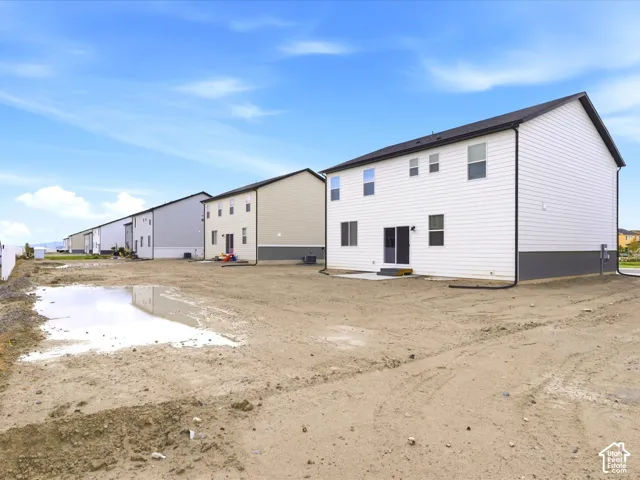 Two-story exterior featuring white horizontal siding, dark metal roof trim, and concrete rear patio