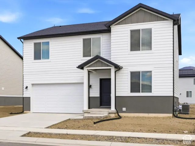 Two-story exterior featuring white horizontal siding, dark grey stucco lower facade, gable roof design, covered front entry, and an attached two-car garage
