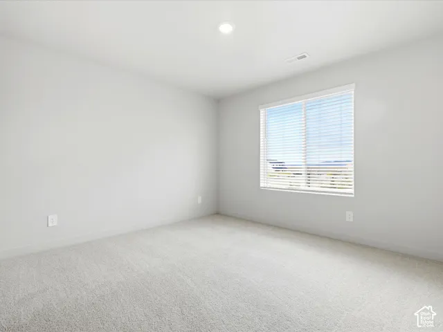 Neutral-toned wall-to-wall carpeting, crisp white walls, recessed ceiling lighting, and a window with horizontal blinds