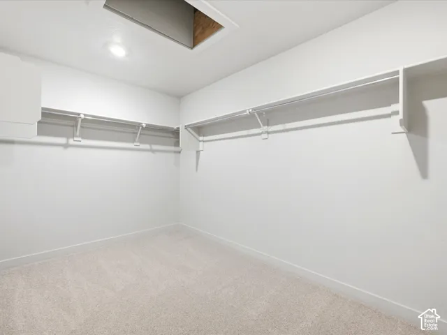 Storage space featuring white wall-to-wall shelving, integrated garment rods, neutral wall-to-wall carpeting, and recessed ceiling lighting