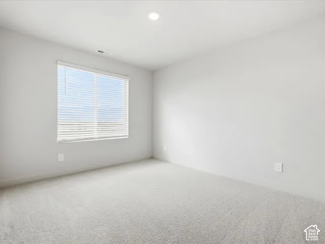 Neutral-toned wall paint, plush carpeting, recessed lighting, and a single-pane window with fitted blinds