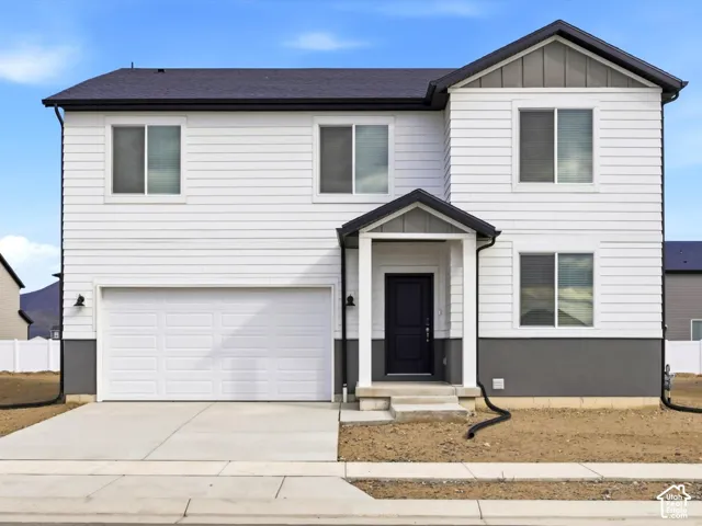 Two-story exterior featuring horizontal siding, a neutral-toned masonry base, a covered entryway with a peaked roof, and an attached two-car garage
