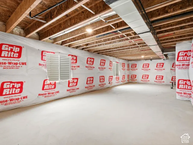 Unfinished lower level featuring concrete flooring, exposed wood joist ceilings, and exterior wall house wrap