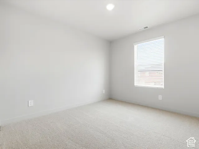 Neutral-toned interior space featuring wall-to-wall carpeting, crisp white walls, and a recessed ceiling light fixture