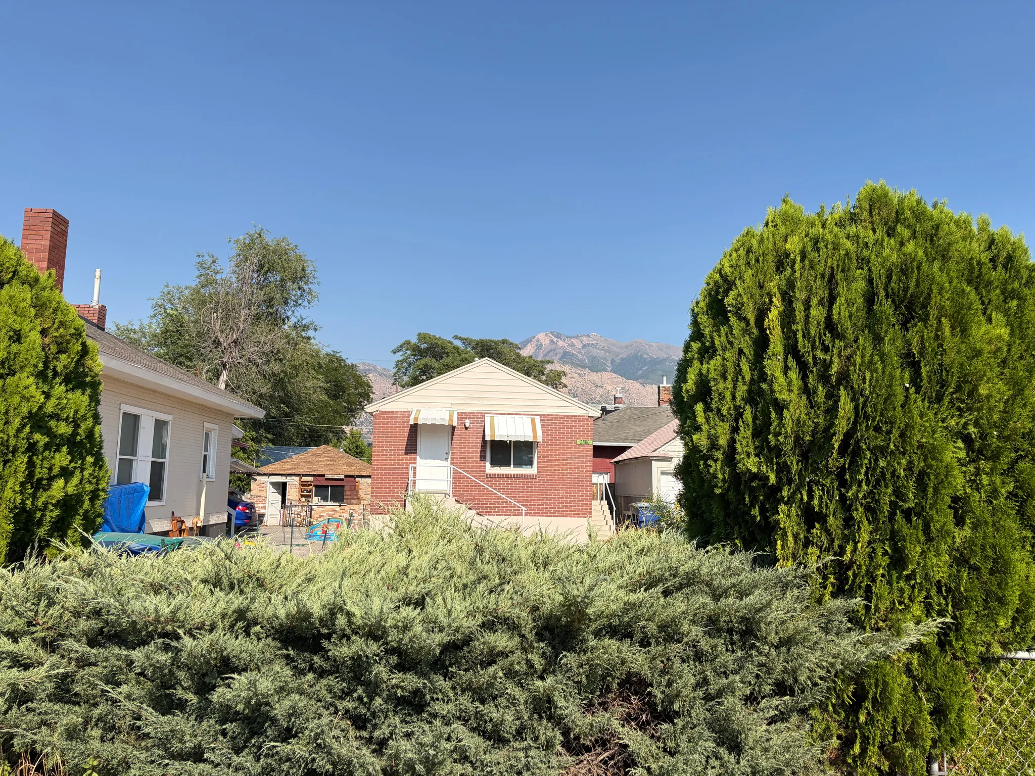 Brick exterior with white door, awning, and mountain backdrop