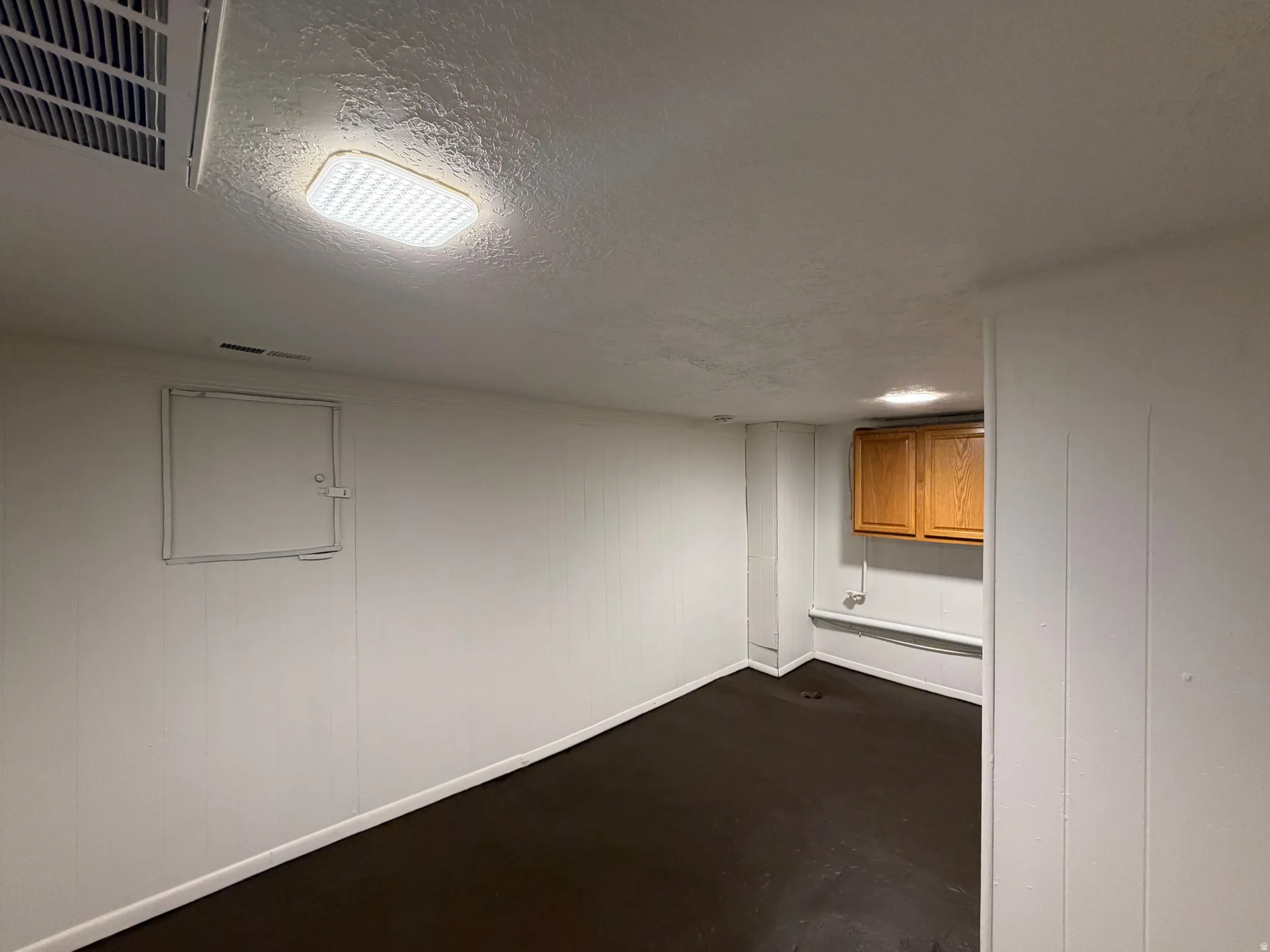 Finished basement space featuring recessed ceiling lighting, smooth drywall construction, and dark wood-finish flooring throughout