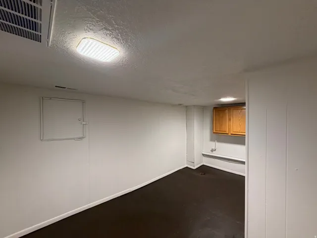Finished basement space featuring recessed ceiling lighting, smooth drywall construction, and dark wood-finish flooring throughout