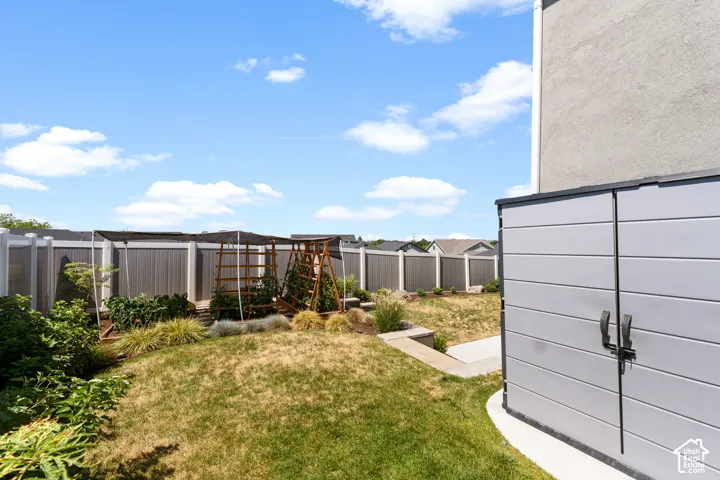 Backyard space featuring a built-in storage shed, tiered landscaping, and a privacy fence