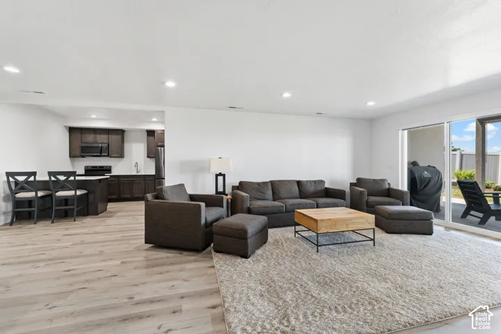 Open-concept living space with light wood-finish flooring, recessed lighting, and a dedicated kitchen area