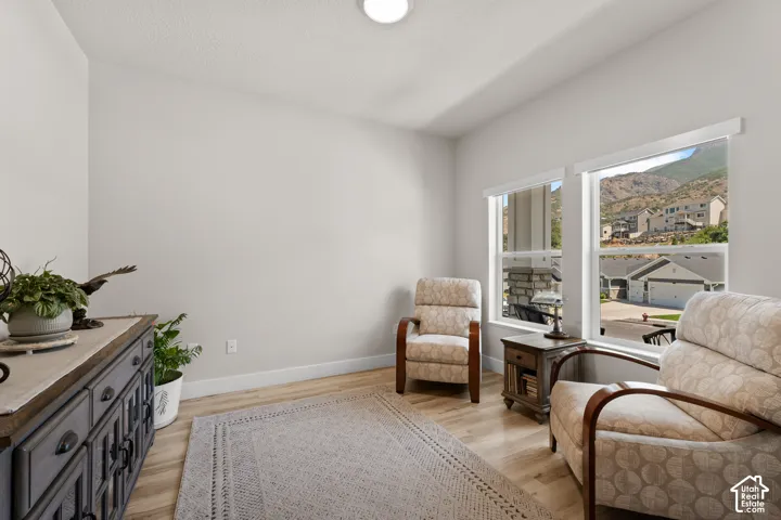 Bright room with light wood-finish flooring, two large windows, neutral wall paint, and a mountain backdrop