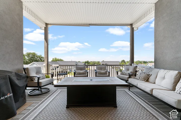 Expansive covered deck featuring composite decking, a textured stucco wall, and a full-height railing