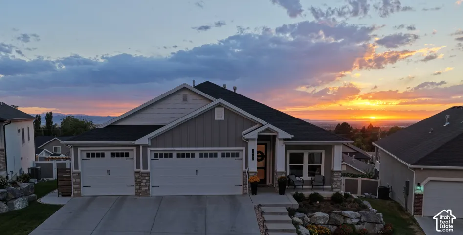Contemporary home with a three-car garage, stone accents, and a covered front porch