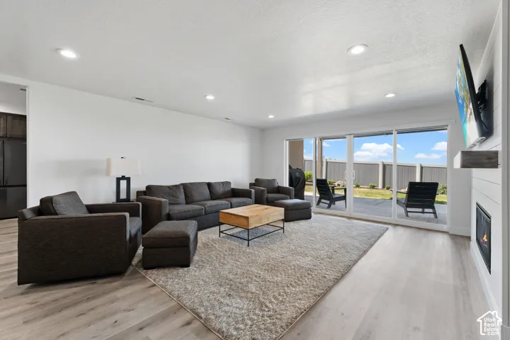 Open-concept living area with wood-finish flooring, recessed lighting, and a modern fireplace with a shiplap surround