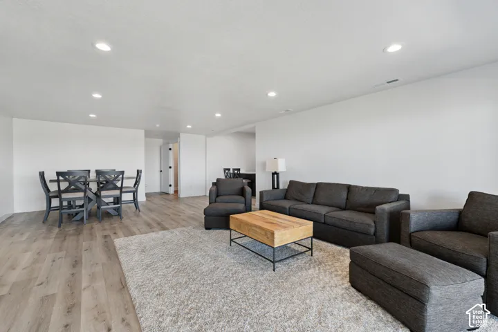 Spacious room featuring light wood-finish flooring, recessed lighting, and white walls