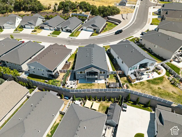 Contemporary residential property featuring a gray exterior, dark shingle roof, and a rear deck with a walkout patio
