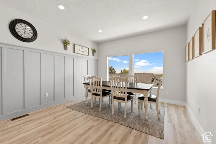 Dining area with light wood-finish flooring, recessed lighting, and board and batten wainscoting