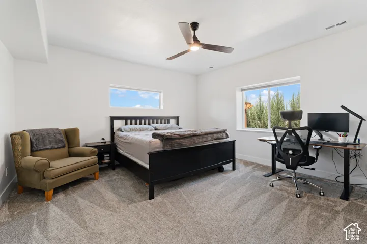 Spacious room featuring light-toned walls, a ceiling fan, and carpeted flooring