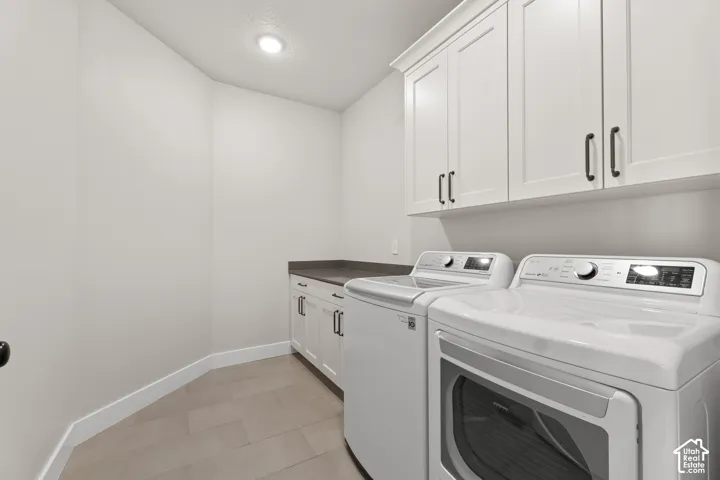 Laundry area featuring white cabinetry, dark countertops, and light-toned flooring