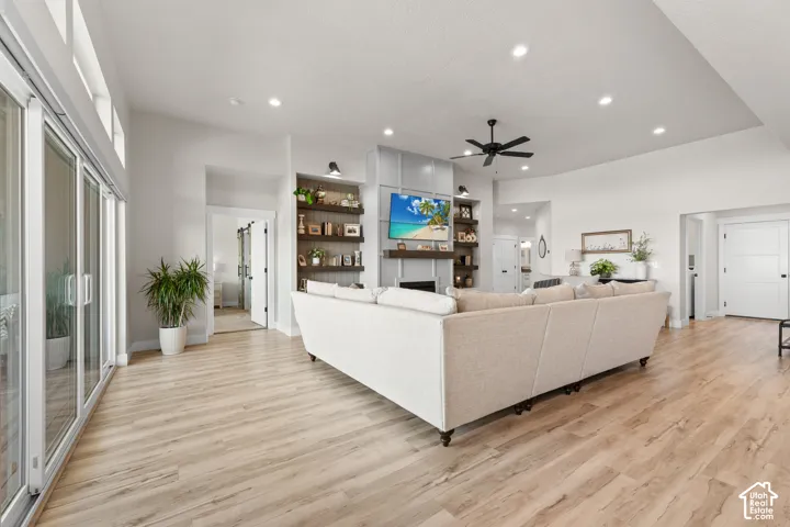 Spacious living area featuring light wood-finish flooring and a built-in media center with open shelving