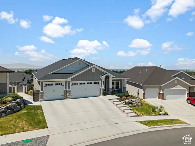 Contemporary ranch-style residence featuring a three-car garage, stone and siding exterior accents, and a covered front porch