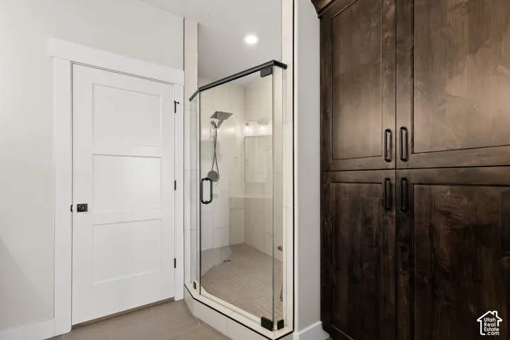 Walk-in shower with clear glass enclosure and dark trim, featuring a rainfall showerhead