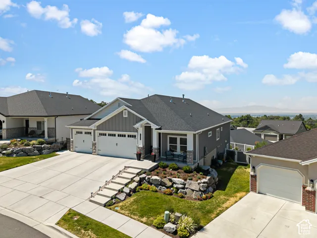 Contemporary residence featuring a three-car garage, concrete driveway, and tiered landscaping