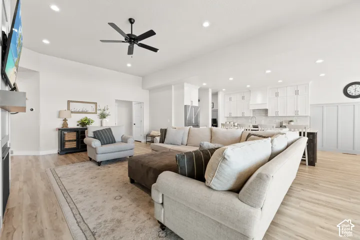 Spacious open-concept living area featuring wood-finish flooring, recessed lighting, and a modern ceiling fan