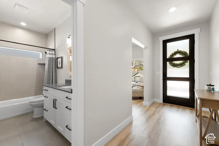 Full bathroom featuring a white vanity with dark countertop, light-toned wall tiling, and a transom window above the tub