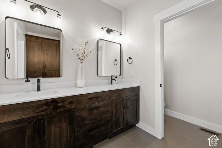 Spa-inspired primary bathroom featuring a dual-sink vanity with dark wood cabinetry, white quartz countertops, and brushed nickel hardware