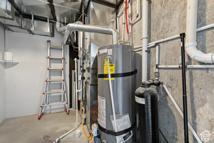 Dedicated utility space featuring a water heater, water filtration system, and exposed ductwork