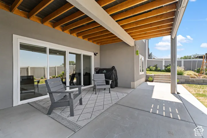 Spacious covered patio with a wood-beamed ceiling and concrete flooring