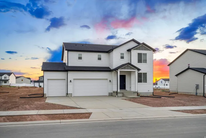 Contemporary two-story residence featuring white siding, a dark roof, and a two-car garage