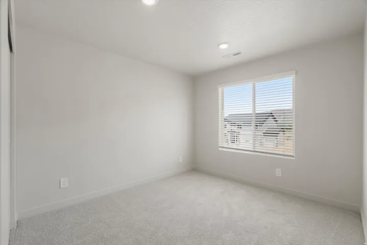 Recessed lighting, light-toned carpeting, neutral wall finishes, and a window with horizontal blinds