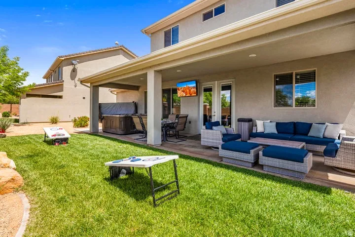 Expansive backyard oasis featuring a manicured lawn, covered patio with integrated ceiling lighting, and composite decking