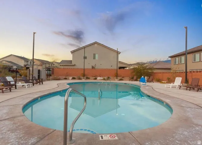 Shaped swimming pool with an integrated entry handrail, surrounded by a concrete pool deck
