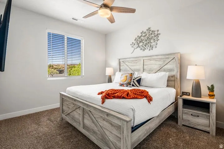 Carpeted room featuring a ceiling fan, a window with blinds, and a light wood-finish bed frame