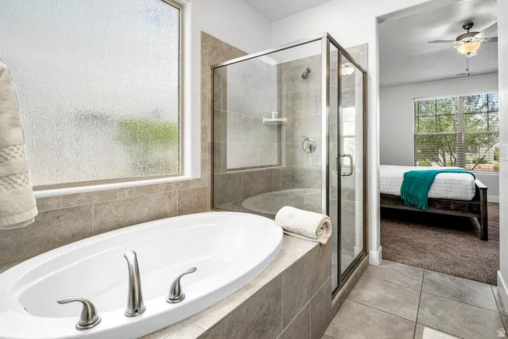Recessed soaking tub with brushed nickel fixtures, glass-enclosed shower with tiled surround, and ceramic tile flooring