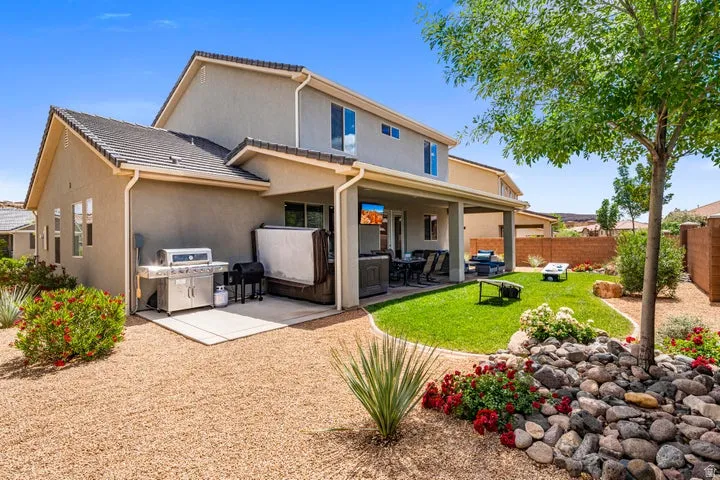 Expansive backyard featuring a covered patio, manicured lawn, and mature landscaping