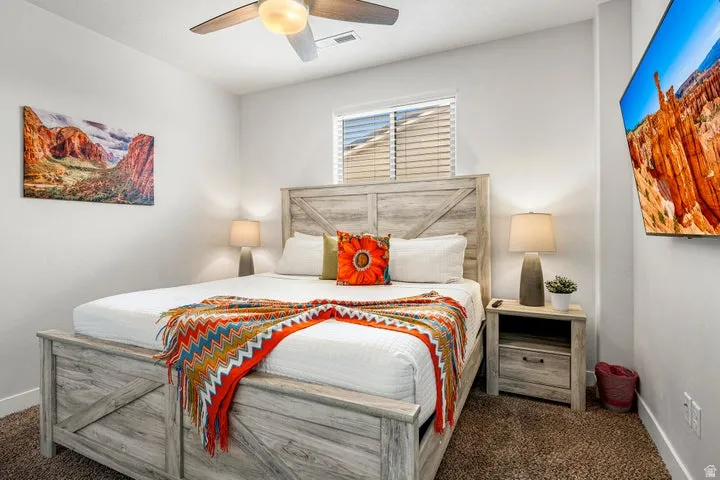Recessed window with horizontal blinds, ceiling fan with integrated lighting, and textured carpet flooring