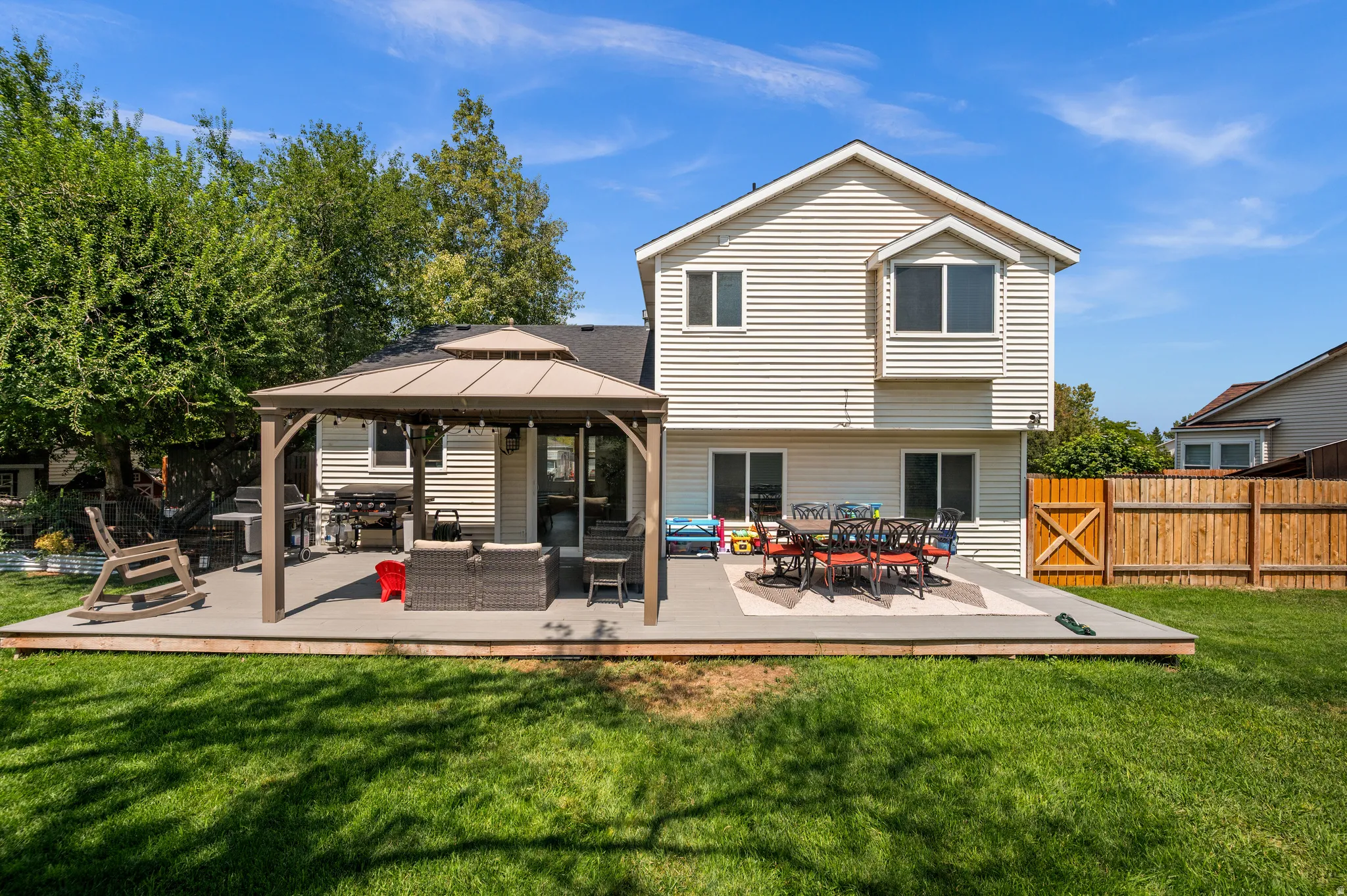 Expansive backyard featuring a large composite deck, covered patio area, and mature perimeter trees