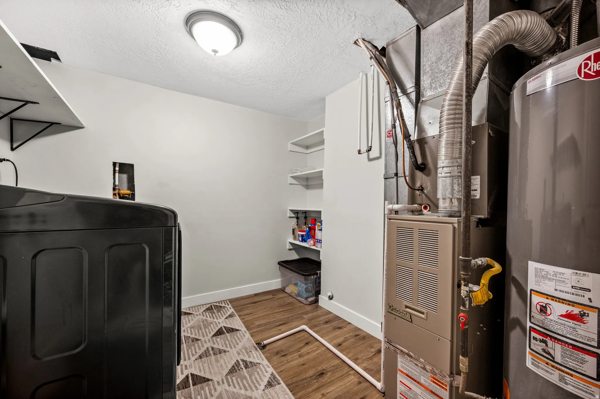 Utility area featuring a water heater, furnace, and wood-finish flooring