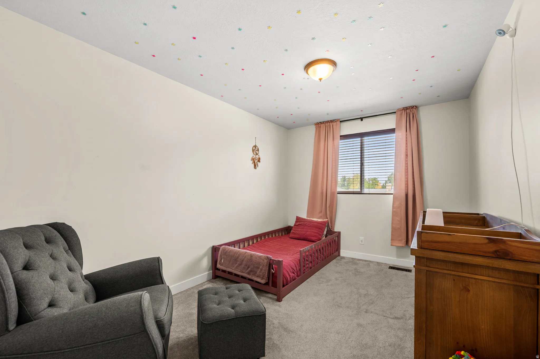 Bright room featuring a window with blinds, carpet flooring, and a ceiling light fixture