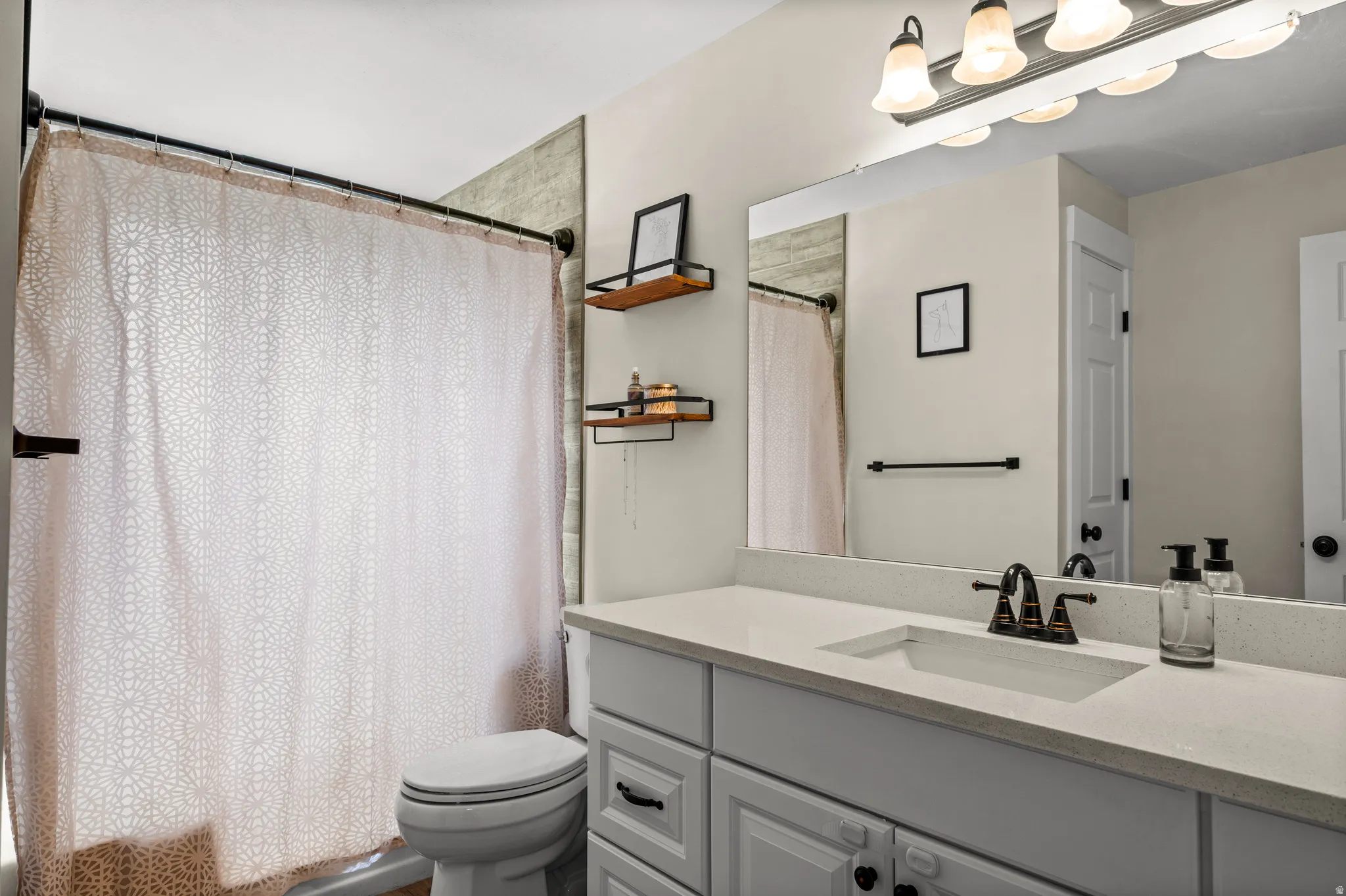 Bathroom featuring a single vanity with a white countertop, an undermount sink, and dark bronze-finish fixtures