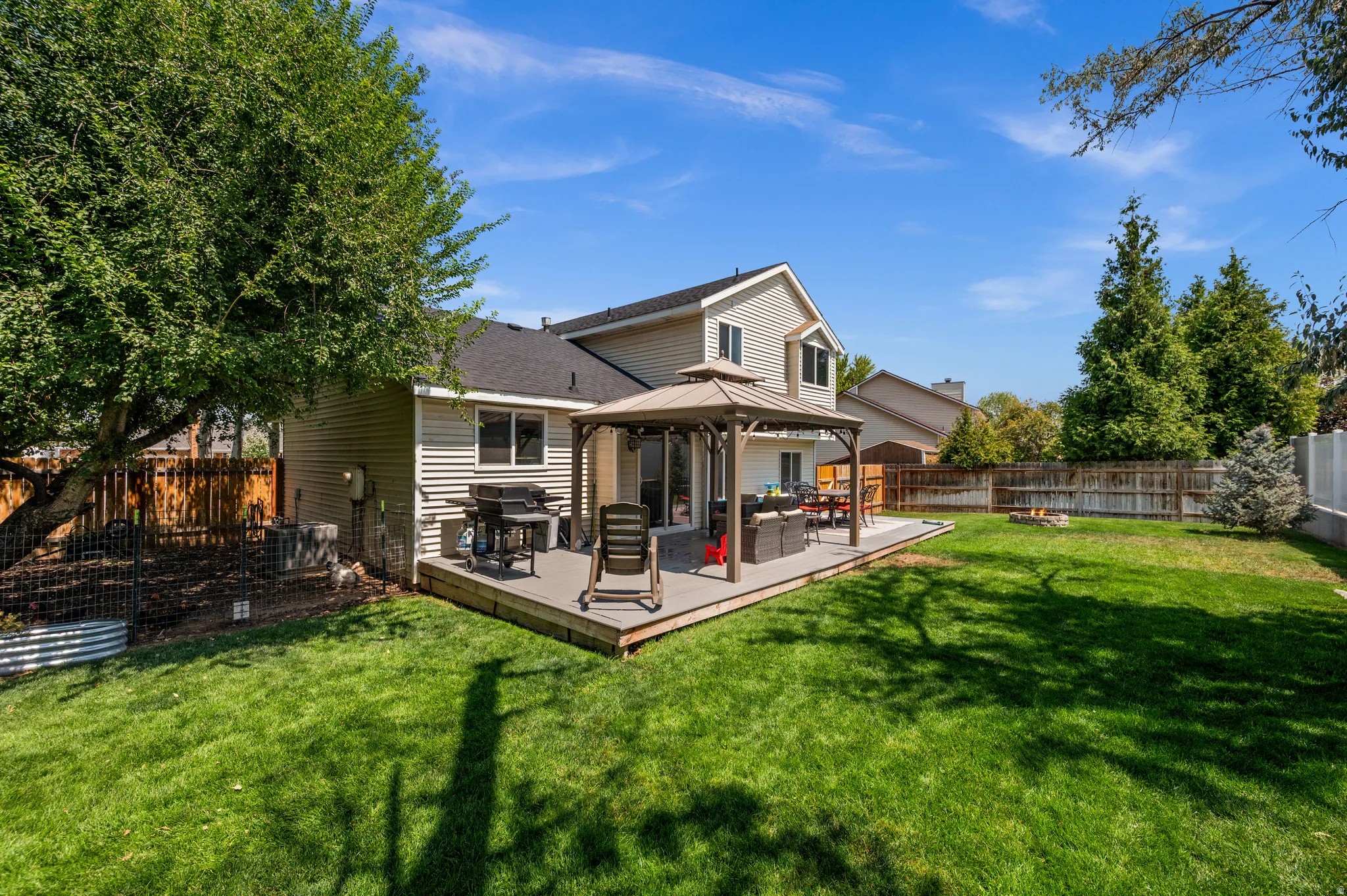 Expansive backyard featuring a large composite deck, a gazebo, and a broad lawn area