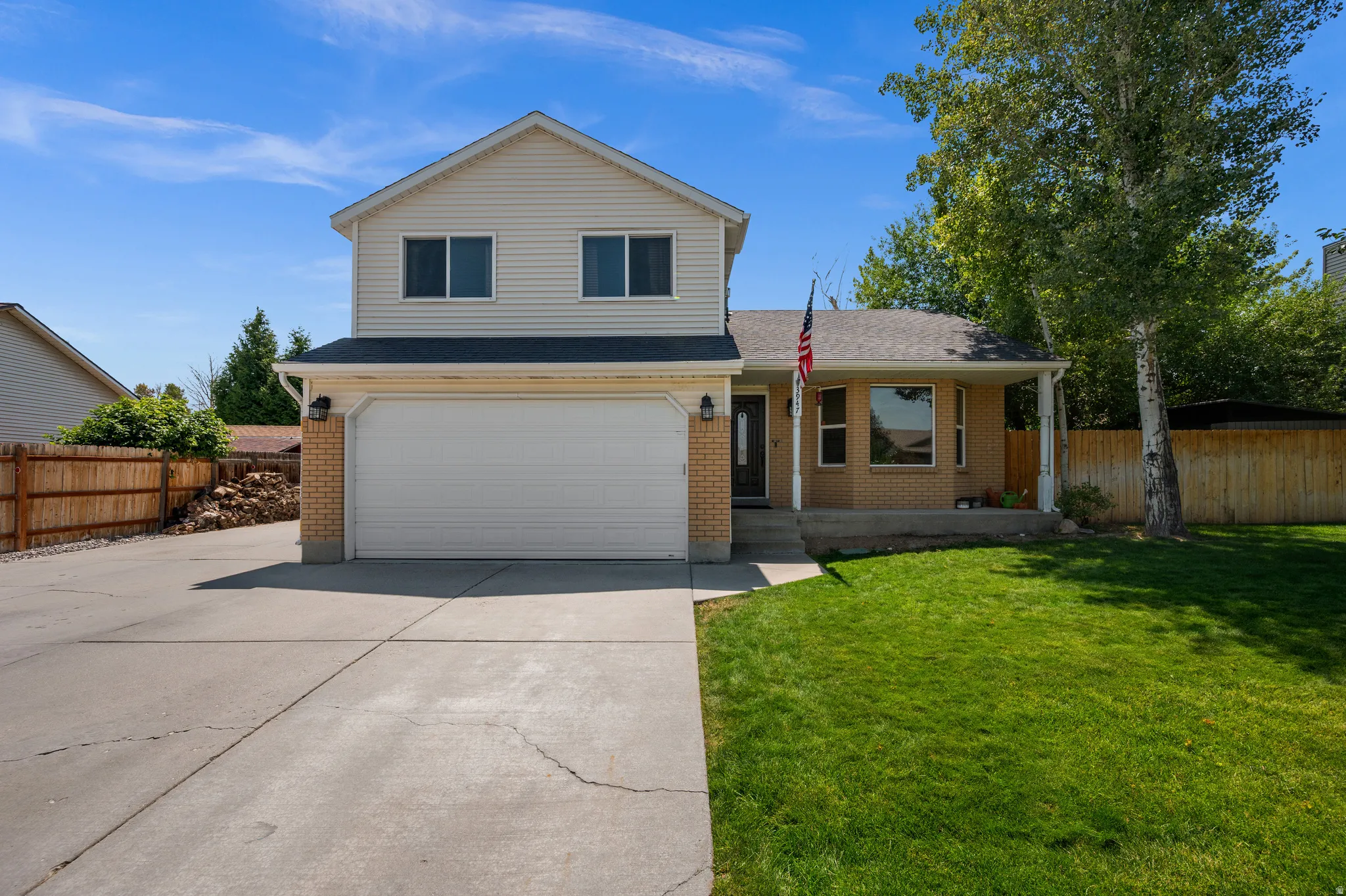 Two-story residence featuring a two-car garage, brick facade accents, a covered front porch, and a bay window