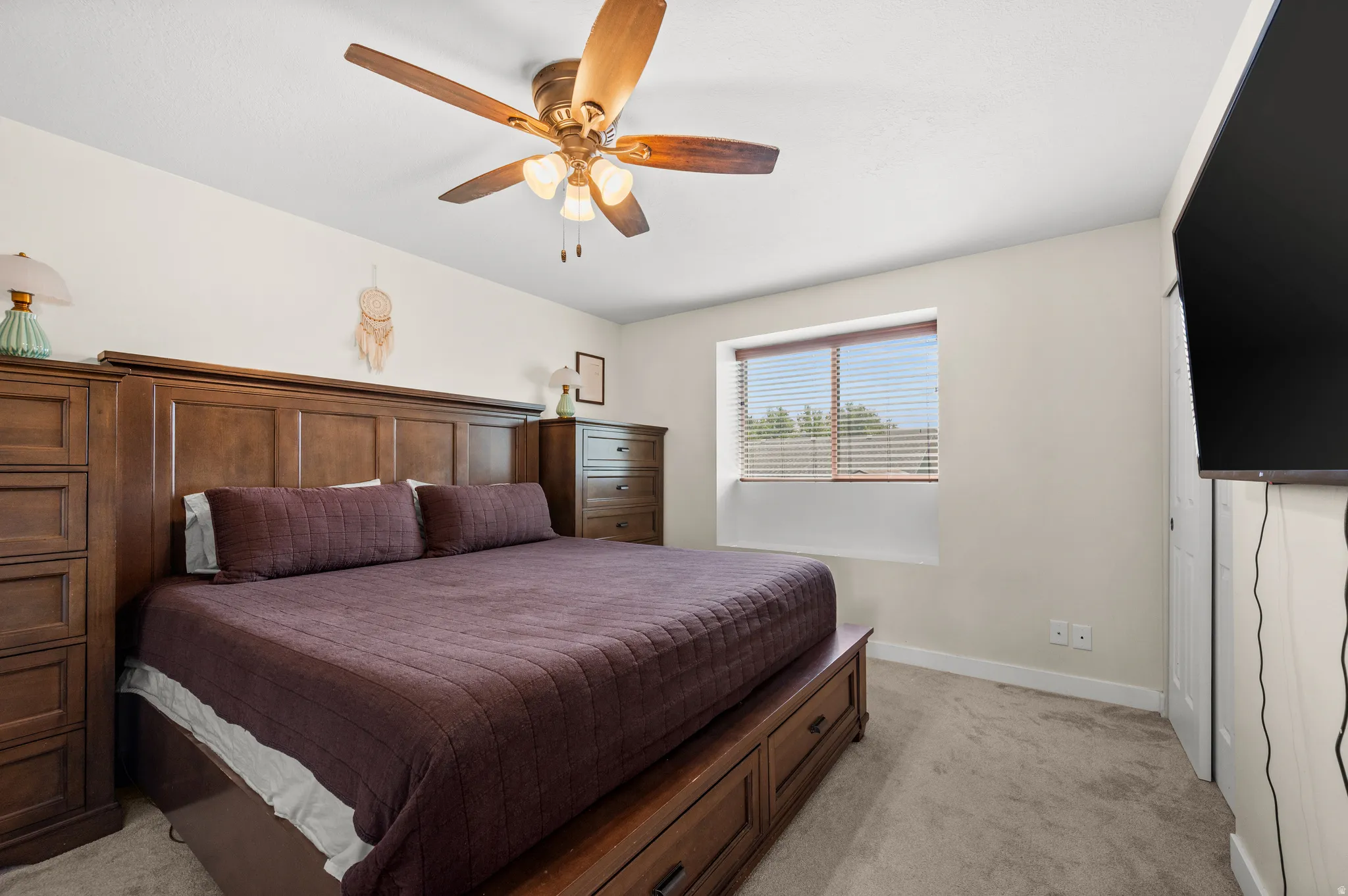 Bedroom featuring a ceiling fan with integrated lighting, a window with horizontal blinds, neutral wall paint, and carpeted flooring