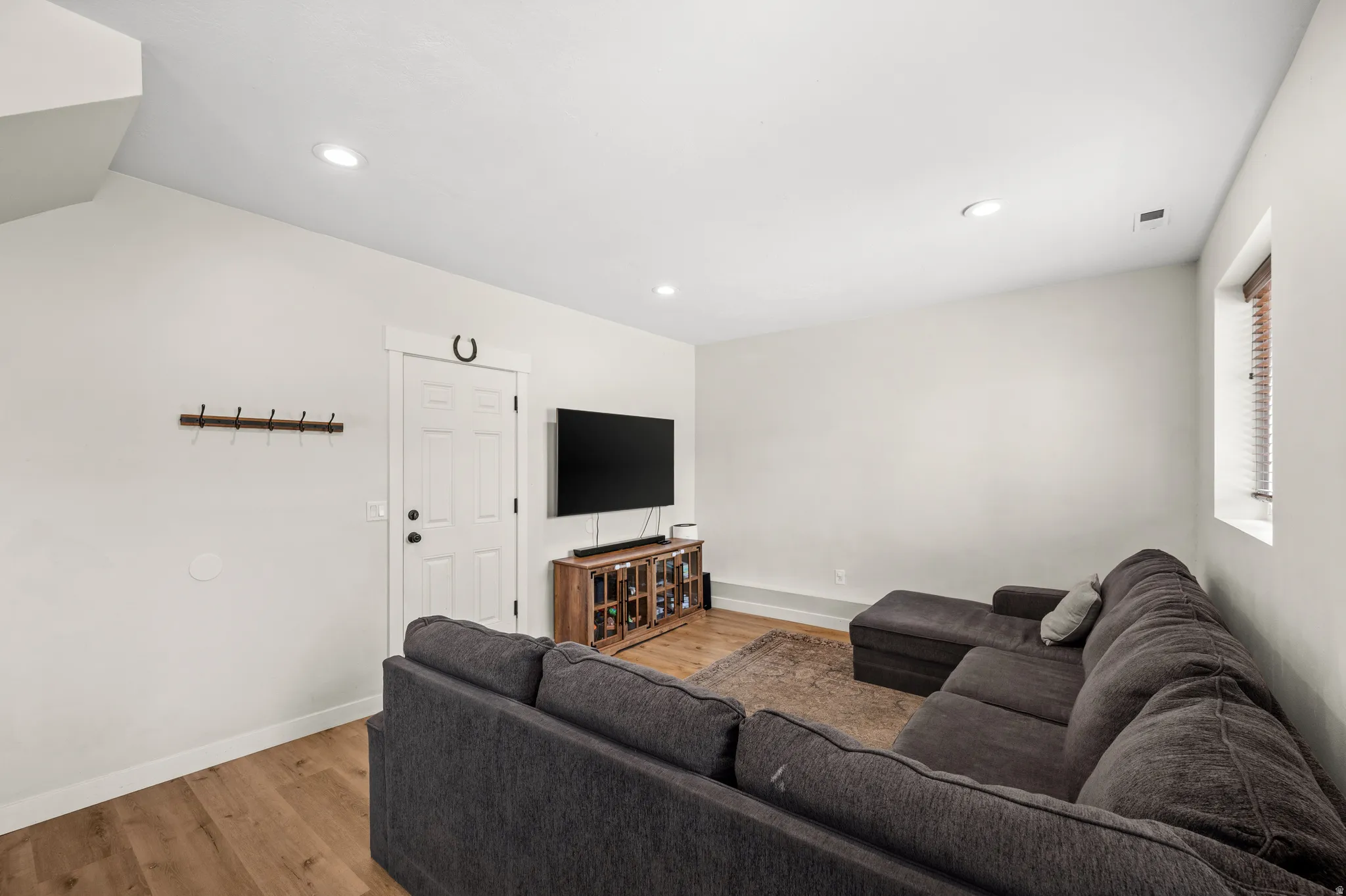 Open living area with recessed lighting and wood-finish flooring