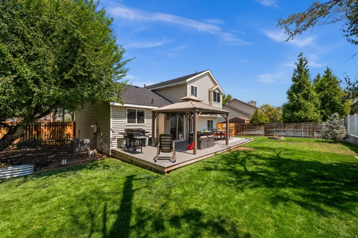 Expansive backyard featuring a large composite deck, a gazebo, and a broad lawn area